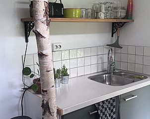Moderne kitchenette in Vakantiehuis in Rucphen met witte tegels en een houten plank in West Brabant.