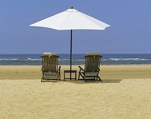 Strandstoelen en parasol aan de Noordzeekust bij Buitenplaats Callantsoog, Callantsoog, Noord-Holland voor ultiem genieten.