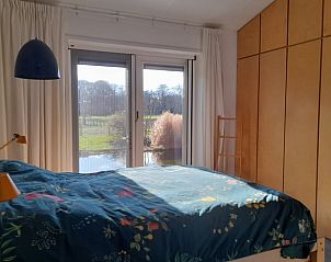 Slaapkamer met uitzicht op tuin in Vakantiehuisje in 's Graveland, Noord-Holland.