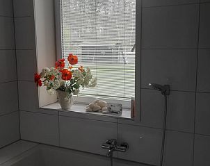 Badkamer met bloemen en bad in Vakantiehuisje in 's Graveland, rustgevend verblijf in Noord-Holland.