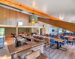 Gezellige eetkamer in De Manderhoeve vakantiehuis in Mander, Twente, met houten details en comfortabele zitplaatsen.