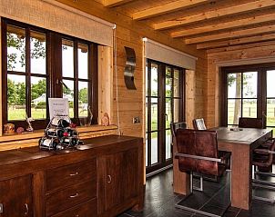 Eetkamer in Houten villa Tine, Den Ham, Twente, met grote ramen die uitzicht bieden op het omliggende landschap.