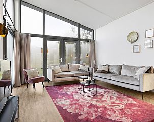 Modern sitting area in Sallandse Heuvelrug 8C vacation home, Twente, with a colorful carpet and lots of natural light.