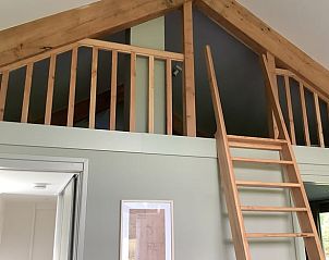 Houten loft in Huisje in De Bult met trap naar bovenverdieping.