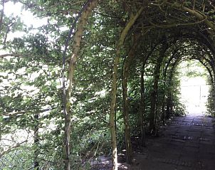 Vakantiehuis in Baars, romantische doorgang met groene bogen in de landelijke omgeving van Overijssel.