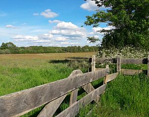 Vakantiehuis in Baars, houten hek met uitzicht op uitgestrekte velden in Noordwest Overijssel.
