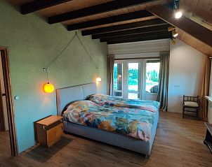 Slaapkamer met tweepersoonsbed en uitzicht op de tuin in Vakantiehuisje in Zalk, Overijssel.