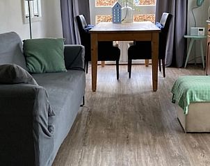 Lichte woonkamer in Vakantiehuisje in Basse, Overijssel, met een comfortabele bank en eethoek.