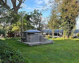 Rustieke hot tub in de tuin van Vakantiehuis in Nigtevecht, Utrecht noord, omringd door groen.