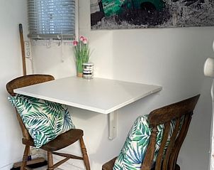 Knusse eethoek in Huisje in 't Goy, vakantiehuis in Utrecht met houten stoelen en tropische kussens.