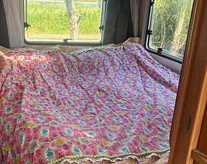 Gezellige slaapkamer in Vakantiehuis in Tull en 't Waal, Utrecht met kleurrijk dekbed en uitzicht op groene natuur.