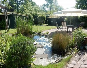 Rustige tuin met vijver en terras bij Achthoek 64, vakantiehuis in Scharendijke, Schouwen-Duiveland, Zeeland.