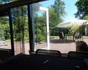 Zonnige tuin met open deur naar terras bij Achthoek 64, vakantiehuis in Scharendijke, Schouwen-Duiveland.
