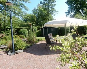 Ruim terras met parasol in de tuin van Achthoek 64, vakantiehuis in Scharendijke, Schouwen-Duiveland.