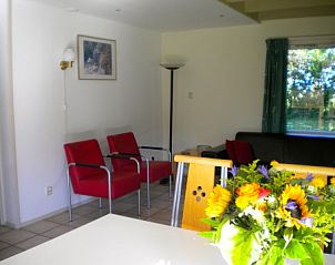 Lichte eetruimte in De Voorpost vakantiehuis, Burgh-Haamstede, met kleurrijke bloemen.