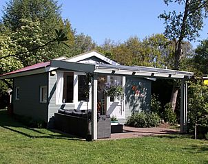 Zijaanzicht van vakantiehuis Pluto in Burgh-Haamstede met terras en omliggende natuur in Zeeland.