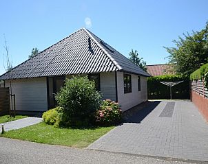 Zijaanzicht van De Parel in Burgh-Haamstede, een vakantiehuis met ruime oprit en groene omgeving.