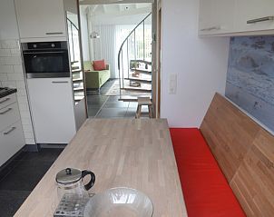 Keuken van De Parel in Burgh-Haamstede, met moderne apparatuur en zicht op de woonkamer.