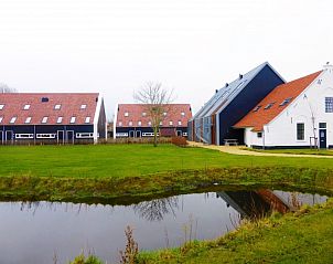Moderne buitenkant van Strandpark De Zeeuwse Kust in Renesse, omgeven door groen en een schilderachtige vijver.