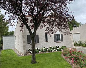 Charmante buitenkant van vakantiehuis Zeelandmuschel in Den Osse, Schouwen-Duiveland, omgeven door groene natuur en bloemen.