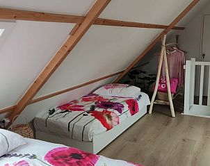 Gezellige zolderkamer in Vakantiehuis in Noordgouwe met houten balken en kleurrijke dekens.