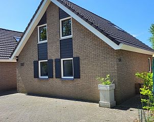Charmante gevel van De Schurveling vakantiewoning in Ouddorp, Schouwen-Duiveland, omgeven door groen.