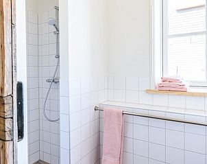 Badkamer met houten deur en moderne douche in Hoeve Plantlust, vakantiehuis Zeeland.