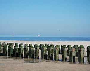 Strand in de buurt van Hoeve Plantlust, Oostkapelle, met houten palen en uitzicht op de zee.