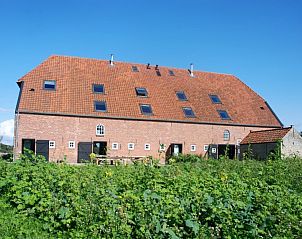 Zijaanzicht van Hoeve Plantlust in Oostkapelle, vakantiehuis met rode dakpannen en groene omgeving.