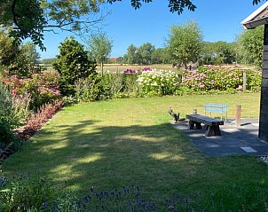 Rustgevende tuin van vakantiehuis Zeewinde in Serooskerke, Walcheren met kleurrijke bloemen en uitzicht op de natuur van Zeeland.