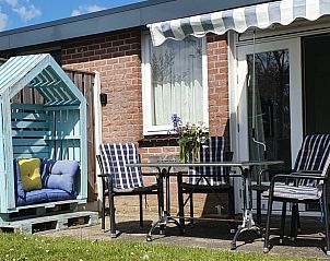 Gezellig terras bij DE ZON IN STEE AAN ZEE vakantiehuis in Serooskerke, Walcheren, met comfortabele zitplek en bloemen.