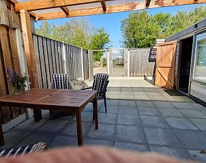 Overdekt terras van DE ZON IN STEE AAN ZEE in Serooskerke, Walcheren, Zeeland, biedt privacy en ontspanning in de buitenlucht.