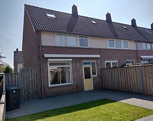 Achterzijde van Ghistel vakantiehuis in Breskens, Zeeland met zonnig terras en omheinde tuin.