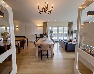 Stijlvolle woonkamer van la Cabane in Nieuwvliet-Bad, met eettafel, open haard en toegang tot terras.