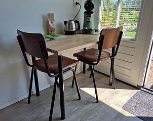 Kleine eethoek in Huisje in Ovezande, Zuid-Beveland, met uitzicht op de tuin en veel natuurlijk licht.