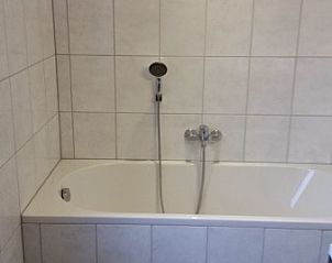 Badkamer van Inlaag24 vakantiewoning in Wolphaartsdijk, Zeeland, met ligbad en tegels.