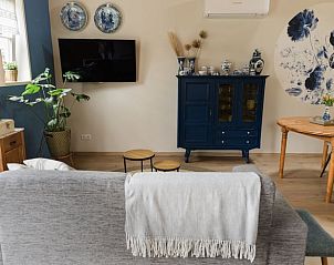 Comfortabele woonkamer in Vakantiehuis in Lewedorp, Zuid-Beveland met blauwe accenten en televisie.