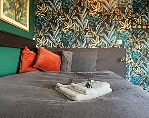 Comfortabele slaapkamer in Huisje in Brandwijk, Brandwijk met kleurrijk behang en zachte kussens.