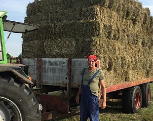 Farmer with hay bales on the land near vacation home Stolwijk, Alblasserwaard, South Holland.