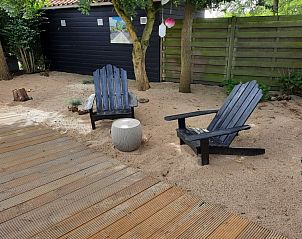 Ontspan in de rustige zandtuin van Chalet Sunrise in Ouddorp, Zeeland, met comfortabele stoelen en omringende natuur.