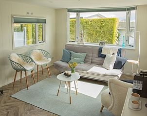 Comfortabele woonkamer in chalet Thuiz, Ouddorp, met uitzicht op de groene omgeving van Goeree-Overflakkee.