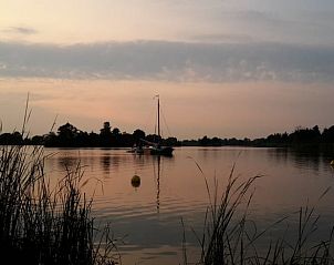 Romantische zonsondergang bij Vakantiehuis in Reeuwijk, met zeilboot op het meer.