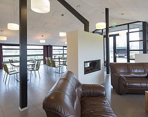 Comfortabele lounge in Vakantiehuisje in Noordeloos, Groene hart, Zuid-Holland met lederen banken en open haard.