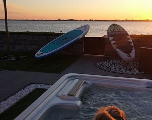 Jacuzzi met uitzicht op meer bij Huisje in Rijnsaterwoude vakantiehuis in Groene Hart Zuid-Holland bij zonsondergang.