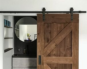 Houten schuifdeur naar badkamer in Huisje in Rijnsaterwoude vakantiehuis in Groene Hart Zuid-Holland.