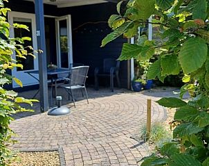 Gezellig terras bij Pinquin 31 vakantiehuis in Rockanje, omgeven door groene natuur in Voorne Putten, perfect voor buiten dineren.