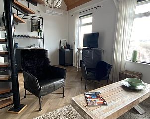 Woonkamer met wenteltrap en zithoek in Vakantiehuis in Klaaswaal, een sfeervol verblijf in Voorne Putten.